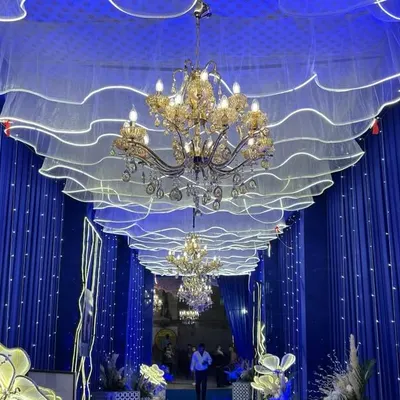 An immersive entrance passage created with royal blue draping, elegant chandeliers, and custom wavy ceiling panels with integrated lighting. We design grand entrances that wow your guests from the first step.
