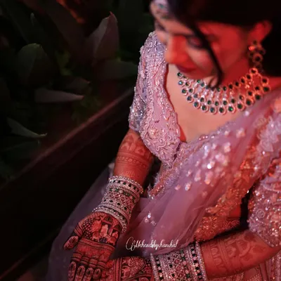 A beautiful bride admiring her dark mehendi stain on her big day. The rich color provides a stunning contrast with her jewelry and outfit.