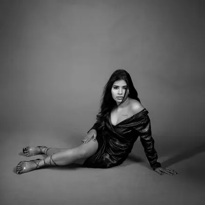 A powerful black and white portrait. The dramatic pose and the stark contrast of the lighting create a strong, emotional image that tells a story of resilience.