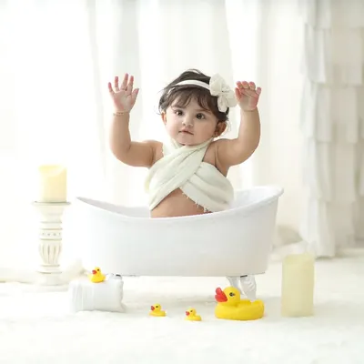 A moment of pure joy as this little one raises her hands during our classic white-themed bathtub session. The minimalist setup with soft lighting puts all the focus on your baby's adorable expression.
