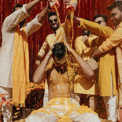 The groom's Haldi ceremony, a moment of pure, unadulterated fun and tradition. The splash of juice adds a dynamic and memorable element to the photograph.