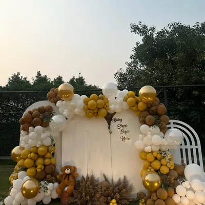 A beautiful outdoor baby shower setup with a teddy bear theme. We used an arch of white, gold, and brown balloons, pampas grass, and a cute teddy bear to create a warm and inviting backdrop for the celebration.