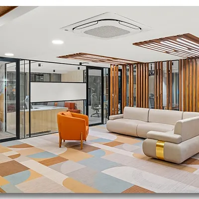 The waiting lounge at Unitus Capital in Bangalore, featuring a colorful geometric rug and modern furniture. The use of glass walls and wooden slats creates a space that is both open and structured.
