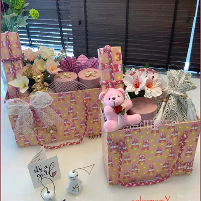 A pair of our signature 'Pretty in Pink' hampers for a baby girl. These gift totes are filled with floral arrangements, a pink teddy bear, and other beautifully wrapped items, complete with an 'It's a girl' announcement card.