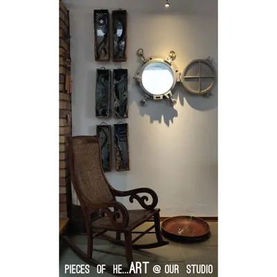 A quiet corner in our studio, which we fill with "pieces of heART". A salvaged ship's porthole mirror and a vintage rocking chair sit together, reflecting our love for objects with a past and stories to tell.