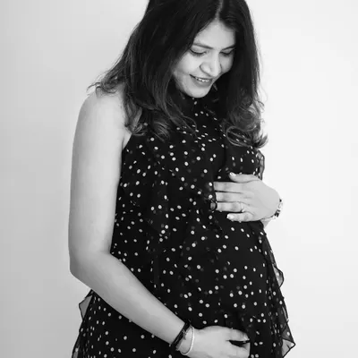 A classic black and white solo maternity portrait. The mom-to-be looks down at her belly with a gentle smile, capturing a quiet and intimate moment of connection with her baby.