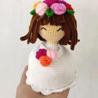 A close-up of a crochet doll I made, showing the detail in her smiling face and the colorful flower crown on her head. This piece is designed as a bust and can be a lovely decorative item.