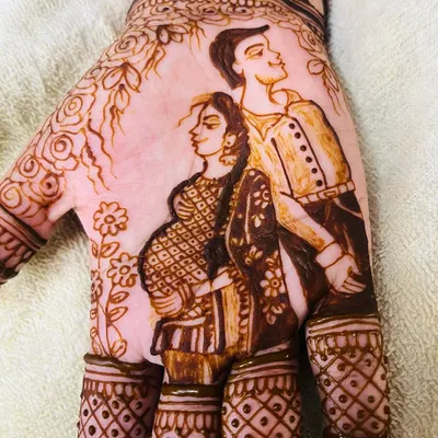 A detailed close up of a maternity couple portrait on the palm. I focus on capturing the likeness and the loving bond between the parents to be, making it a central part of the baby shower mehendi design.
