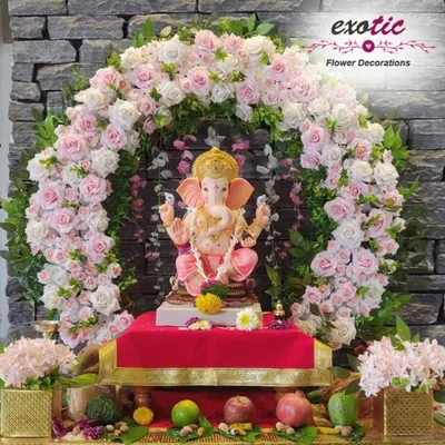 A beautiful and classic Ganpati decoration. This perfectly shaped arch of pink and white roses provides a delicate and respectful frame for the Ganesha idol, set against a stone wall.