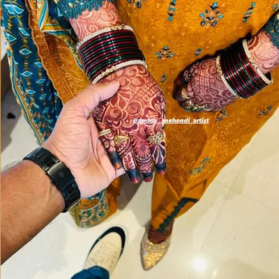 A beautiful moment captured between the couple, with the bride's rich henna stain and bangles on full display.