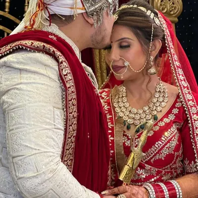 A beautiful, candid moment between the bride and groom. Her classic red lehenga and soft glam makeup create a timeless picture of wedding day happiness.