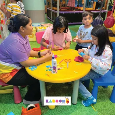 A group of children gathered around a yellow table, fully engaged in a paper flower craft activity with the help of our instructor. Busy hands lead to happy hearts!
