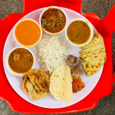 A complete vegetarian thali served at a wedding in Pen. It includes multiple curries, dal, rice, puri, naan, and dessert, offering a full meal experience.