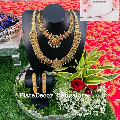 A complete bridal jewellery set, including necklaces and bangles, displayed on a professional bust. The platter is decorated with fresh flowers and greenery for an elegant presentation.