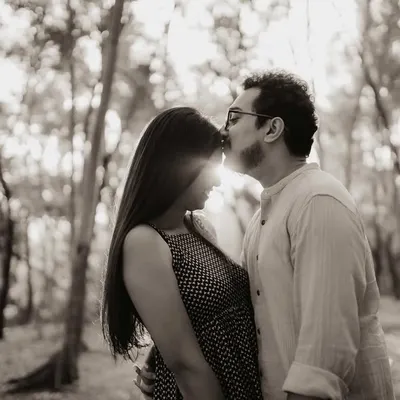 A tender forehead kiss captured in black and white, with the sun creating a beautiful flare behind the couple. This silhouette effect highlights their forms and the intimacy of the gesture.