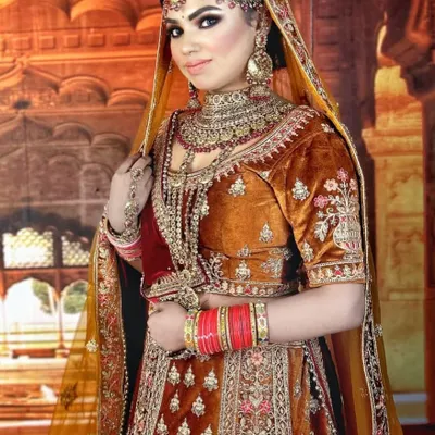 A classic bridal look in a rich rust-orange velvet. This rental lehenga features traditional embroidery and is paired with heavy kundan jewellery, perfect for a timeless wedding ceremony.