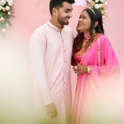 A beautiful, candid moment between a couple dressed in coordinated pink ethnic wear. The bride-to-be is wearing my hot pink Rajputani-style outfit.