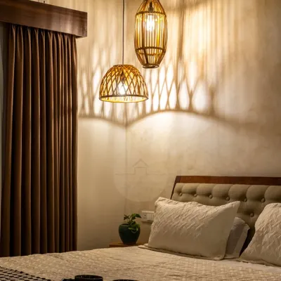 This cozy master bedroom shows the transformative power of lighting. The rattan pendant lights cast beautiful shadows on the textured wall, turning the space into a magical and intimate retreat at night.