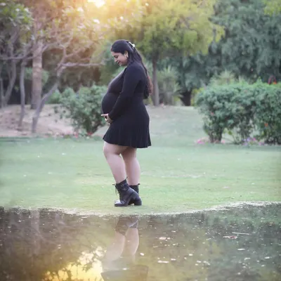 Two reflections, one soul. This artistic outdoor shot uses the water's reflection to mirror the miracle of motherhood, all set against the warm glow of the setting sun.