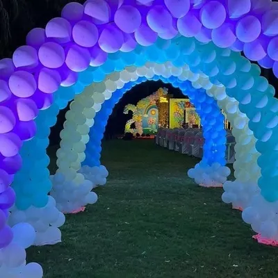 An incredible rainbow balloon tunnel entrance for a Cocomelon party, lit from within to create a magical pathway for guests.
