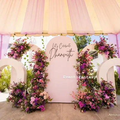 A stunning floral stage created for Dhanvith's celebration. I used modern white arches and adorned them with an abundance of fresh flowers in shades of purple and pink to create a breathtaking photo backdrop.