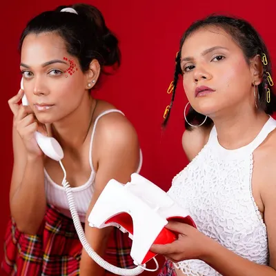 A playful and retro-inspired editorial shot. The bold red background, vintage telephone prop, and Y2K styling come together to create a fun and vibrant story with a strong narrative feel.