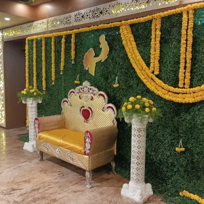 This is a classic setup for a Haldi or Mehendi ceremony. We used a full artificial green wall backdrop, decorated with traditional marigold flower garlands and a custom cutout, paired with a golden throne for the main seating.