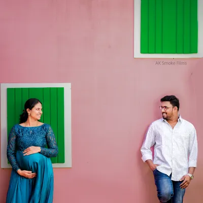 A modern and stylish couple's portrait using bold colors and composition. The pink wall and green windows create a vibrant, playful backdrop for this contemporary maternity shoot.