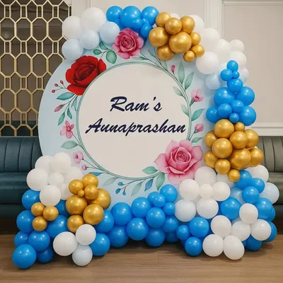 A beautiful backdrop for Ram's Annaprasan (first rice-eating ceremony). The circular backdrop has a floral design and is framed by a blue, white, and gold balloon arrangement.