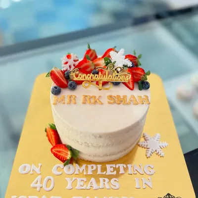 A beautiful cake to celebrate a remarkable achievement. This fresh fruit cake was made to honor an employee completing 40 years with the Ispat family, featuring a congratulatory message and elegant design.