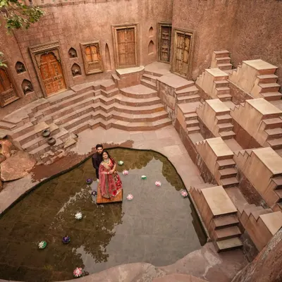 A breathtaking wide shot at the Anokhi Baoli, a stunning heritage location in Faridabad. The intricate architecture of the stepwell provides a majestic setting for a truly epic pre-wedding portrait.