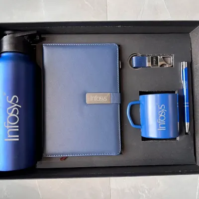 This is a popular welcome kit configuration, shown here in a professional blue for Infosys. The set includes a 750ml bottle, A5 diary, steel mug, pen, and keychain, with the logo clearly displayed on each item.