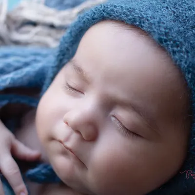 In these early days, every detail matters. This close-up of a sleeping baby in a blue bonnet highlights the delicate features I love to capture.