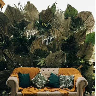 Personal touches make a wedding special. We designed this cozy seating area with a custom "Better Together" neon sign against a backdrop of tropical leaves, perfect for a modern Mehendi or pre-wedding photoshoot.