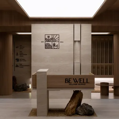 The reception, where the brand's logo is subtly integrated into a monolithic stone wall. The space is defined by clean lines, natural materials, and a sense of serene order.