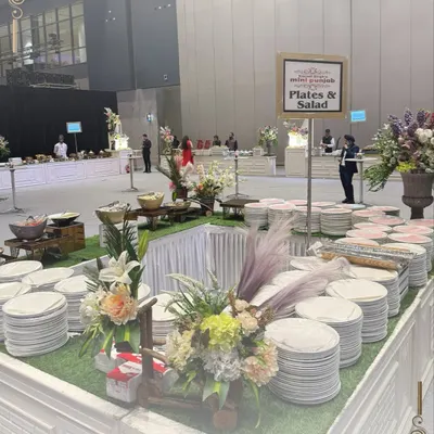 An elegant plates and salad station. The setup with fresh flowers and a grass-like base creates a fresh and inviting look.