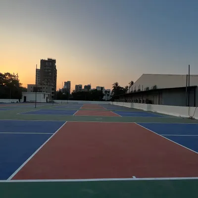 Welcome to the Maniac Pickleball Arena in Vile Parle. This is a wide view of our multiple international standard terrace courts, captured during a beautiful Mumbai sunset, ready for your next game.