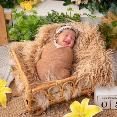 A newborn wrapped snugly in a brown swaddle smiles blissfully in their sleep. Capturing these fleeting dream-filled smiles is one of the most rewarding parts of a newborn session, a moment of pure, unscripted joy.