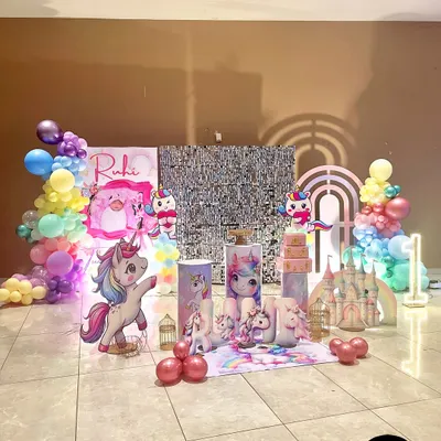The main stage for Ruhi's unicorn-themed first birthday. This setup features a silver sequin backdrop, pastel balloon garlands, a unicorn castle, and multiple custom props.