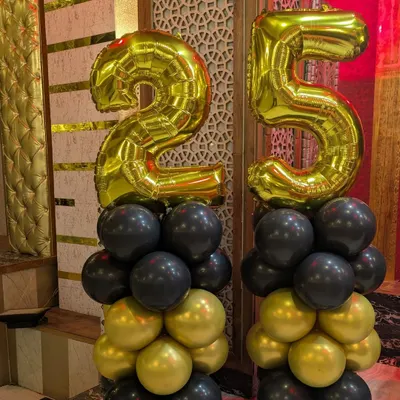 Balloon pillars for a 25th anniversary, featuring gold foil numbers on top of black and gold balloon columns.