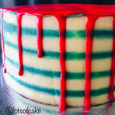 A close-up of my Christmas striped cake. I carefully created the green and white stripes with buttercream and added a dramatic red drip for a festive look that's perfect for holiday parties.