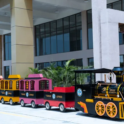 The 'Konark Express' in action. The train features multiple colorful carriages, providing a fun and secure way for young students to travel from the main gate to their classrooms, away from any vehicle traffic.