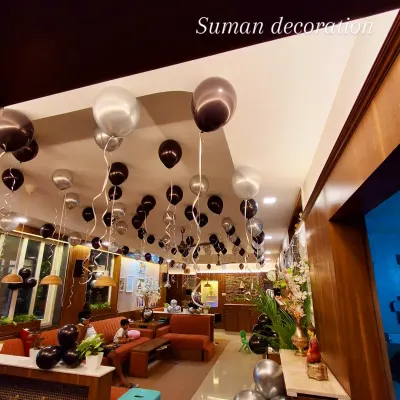 A view of a room decorated with black and silver helium balloons floating on the ceiling. This is an easy way to decorate a large space for a birthday or party.