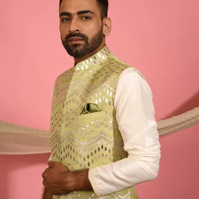 This pistachio green Nehru jacket is a fresh and modern choice for daytime events. The geometric foil work catches the light beautifully, and the matching pocket square adds a final touch of polish.