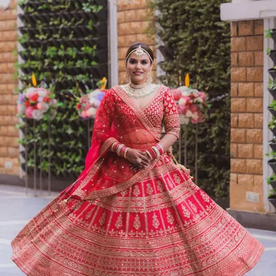 A full, twirling shot of this bride shows off her regal red lehenga. The makeup was designed to be timeless, with luminous skin and softly defined eyes that ensure she looks breathtaking from every angle.