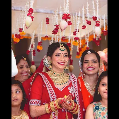 A candid moment of pure joy. This stunning North Indian bride is surrounded by her family during her pheras. I created a classic red-and-gold bridal look for her, complete with a traditional low bun and gajra.