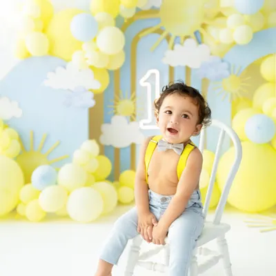 The pre cake calm! Dressed in an adorable bow tie and suspenders, this little man is all smiles in his sunshine themed first birthday setup, ready for the celebration to begin.