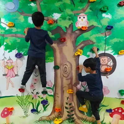 Two young ninjas work together to scale the tree-themed climbing wall. This activity is great for building strength, coordination, and confidence.