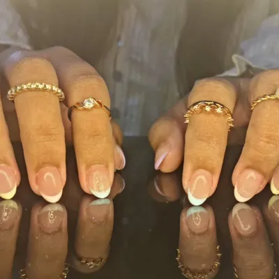 A classic and clean French manicure with crisp white tips on perfectly shaped oval nails, reflecting beautifully for a timeless look.