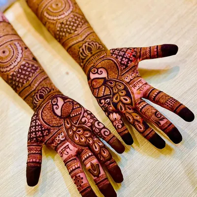 The peacock is a symbol of grace and beauty, making it a popular request for bridal mehendi. Here, it is the centerpiece of the palm design, created with fine, detailed feather work.